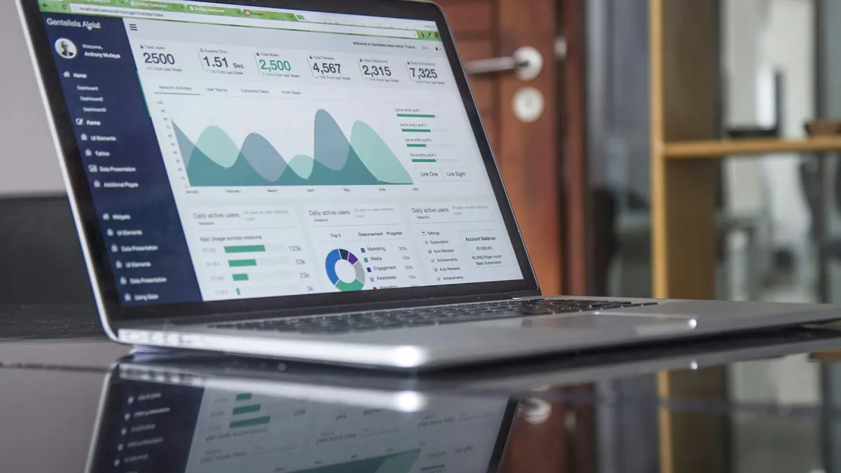 A laptop showing sales charts on a glass table